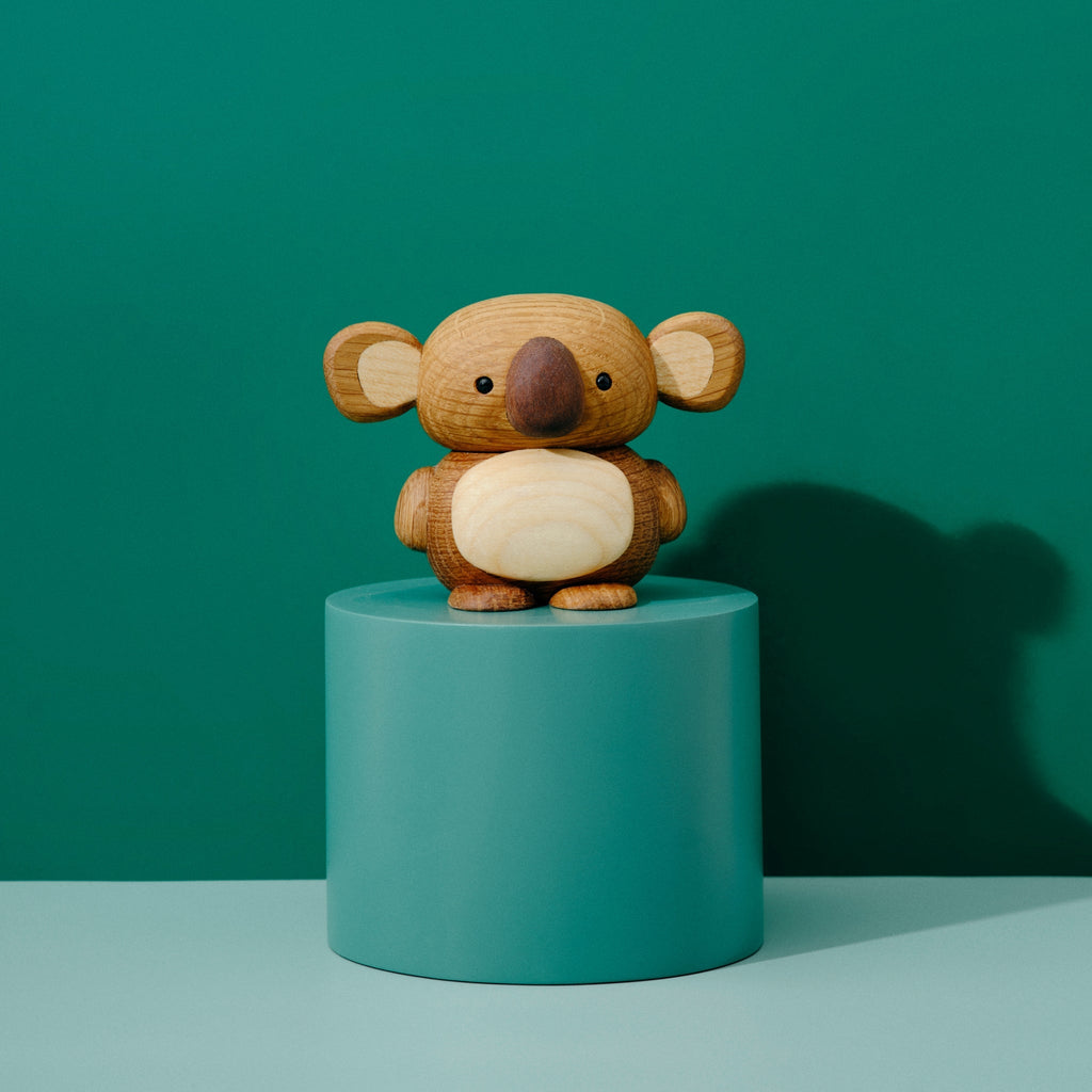Kozi seul sur un socle vert devant un fond vert.