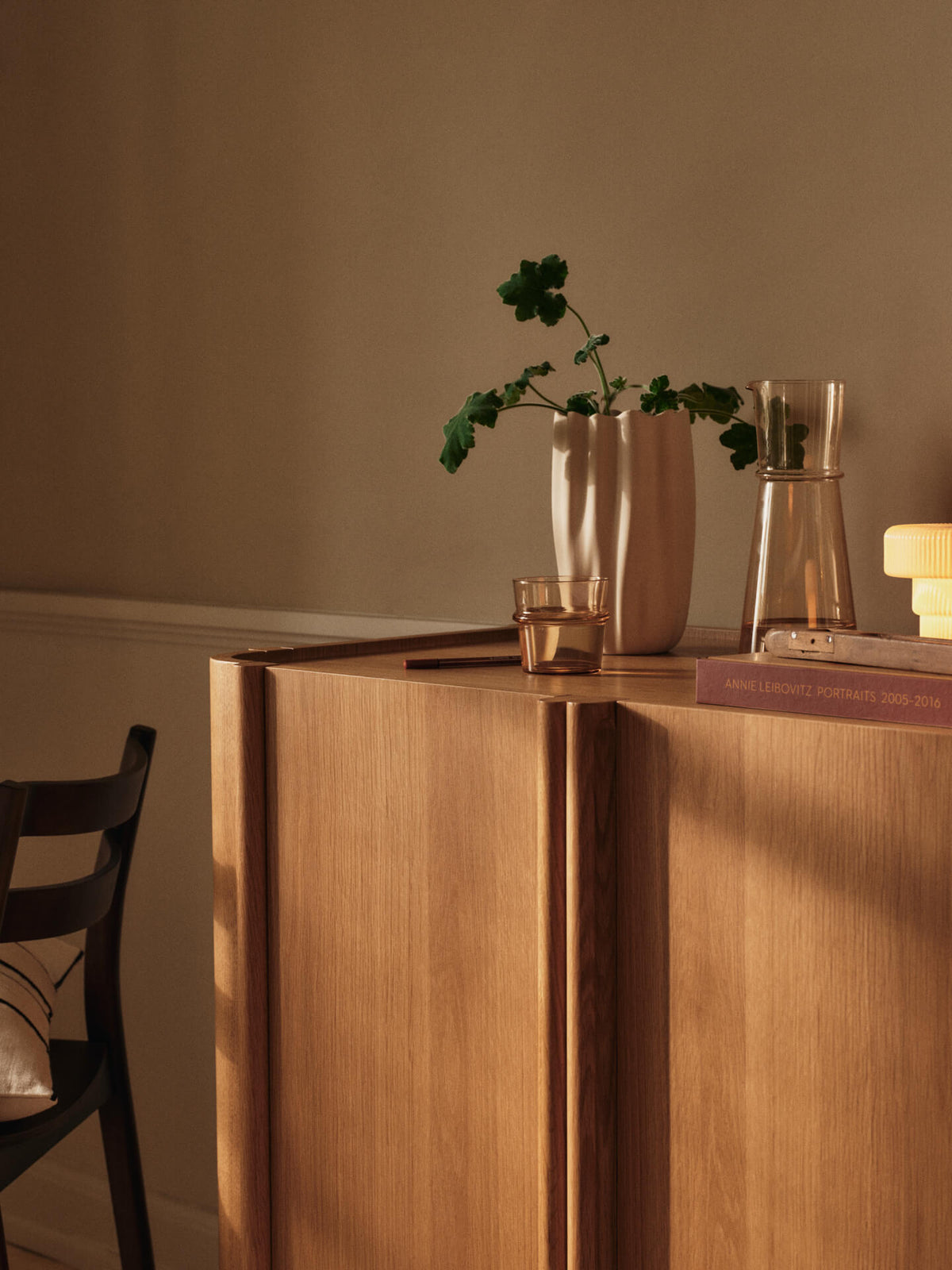 Vase Nium blanc cassé avec des branches sur un meuble en bois